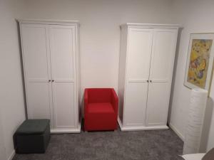 een rode stoel in een kamer met twee witte kasten bij Hexenstube Jorjina - WLAN - Garten- tolles Bad -Wandern -Mountainbike - Motorradurlaub in Braunlage +25 foto's