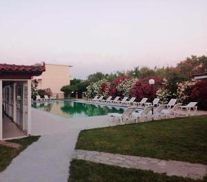 a pool with white lounge chairs next to a building at Lunzi Verde in Laganas
