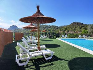 a group of chairs and umbrellas next to a pool at Casa Rural Puente del S,egura in Elche de la Sierra