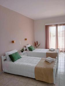 two beds in a hotel room with green pillows at Lunzi Verde in Laganas