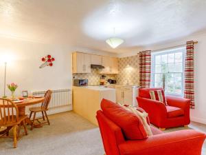 een keuken en een woonkamer met rode stoelen en een tafel bij 1 Bed in Keswick 86394 in Rosthwaite
