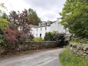 ein weißes Haus mit einer Steinmauer neben einer Straße in der Unterkunft 1 Bed in Keswick 86394 in Rosthwaite