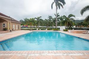 uma grande piscina com palmeiras ao fundo em Ocho Rios Drax Hall Country Club 2 Bed Villa Getaway em Mammee Bay