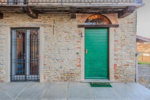 a green door on the side of a brick building at Serra Alta Langa Holiday Home in Trezzo Tinella