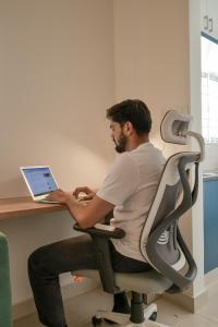 a man sitting at a desk with a laptop at HomeSlice Whitefield - 1BHK/ 2BHK Apartment/ Studio Room in Bangalore