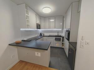 eine Küche mit weißen Schränken und einer schwarzen Arbeitsplatte in der Unterkunft Paris 15 min Appartement tout confort 6 couchages in Vitry-sur-Seine
