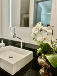 een badkamer met een wastafel en een vaas met bloemen bij Hotelcity in Brusque