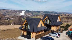 a house with a black roof on a hill at Domki na Gawlakach in Zakopane