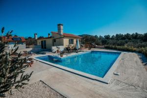 a swimming pool in front of a house at Holiday home Jukan in Vrulje