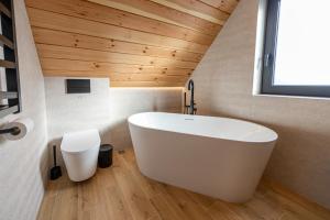 une baignoire blanche dans une salle de bain avec un plafond en bois dans l'établissement Domki na Gawlakach, à Zakopane 39 autres photos