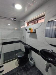 a bathroom with a black toilet and a sink at Habitaciones con baño privada Quiroga in Bogotá