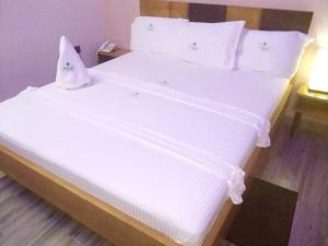 a large white bed with white sheets and pillows at CELEBRITES HOTEL in Ouidah