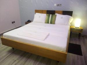 a bedroom with a large bed with white sheets and a lamp at CELEBRITES HOTEL in Ouidah