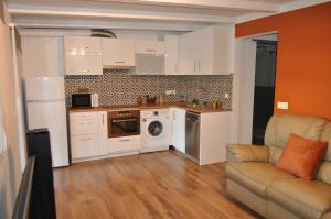 una cocina con armarios blancos y un sofá en una habitación en Near Beach, en Sant Pere Pescador