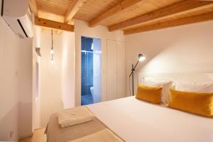 um quarto com uma grande cama branca com almofadas amarelas em Casinha da Póvoa -Turismo Aldeia em Castelo de Vide