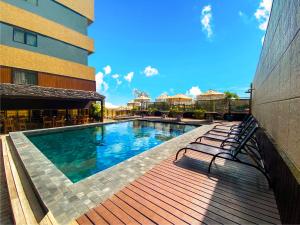 a swimming pool with benches next to a building at Magna Praia Hotel in Fortaleza
