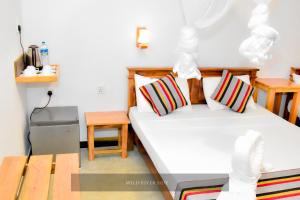 a room with two beds and a table and a bed at Wild River Side in Udawalawe