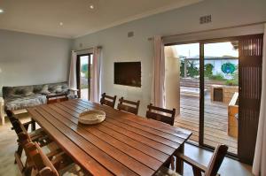 a dining room with a wooden table and chairs at Sandy Feet Langebaan in Langebaan