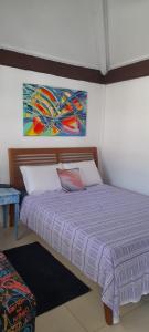 a bedroom with a bed with a purple comforter at Hospedagem Tucanos in Búzios