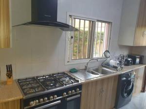 uma cozinha com um fogão, um lavatório e uma janela em Poolside Garden em Brufut