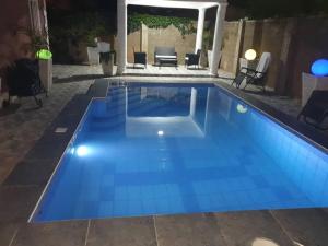 uma piscina à noite com água azul em Poolside Garden em Brufut