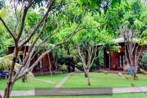 a garden with trees in front of a house at Wild River Side in Udawalawe