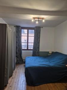 um quarto com uma cama azul e uma janela em La Pomme em Douvres-la-Délivrande