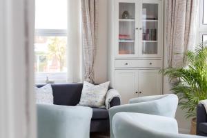 - un salon avec un canapé bleu et des fauteuils blancs dans l'établissement Poole Park House, à Poole