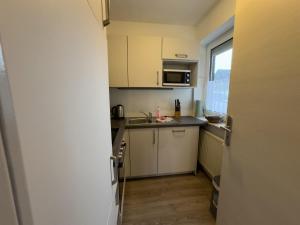 a small kitchen with white cabinets and a sink at Windfang 1 in Hooksiel in Wangerland
