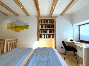 1 dormitorio con cama, escritorio y estante para libros en Nostalgie di un tempo nelle Dolomiti, en Pergine Valsugana
