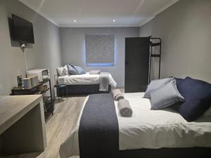 a room with two beds and a flat screen tv at @241 Enkeldoorn Guesthouse in Pretoria