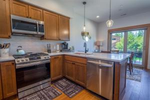 a kitchen with wooden cabinets and a stainless steel stove at Suncadia 2 Bdrm Village Chalet Contemporary Cabin in Cle Elum