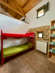 a red bunk bed in a room with wooden ceilings at Albergue Valle de Arbas in Cubillas de Arbas