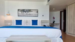 1 dormitorio con 1 cama grande con almohadas azules y blancas en Wyndham Rio Barra, en Río de Janeiro