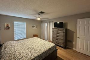 Schlafzimmer mit einem Bett und einer Kommode mit einem TV in der Unterkunft Lake View Meadows Condo in Sarasota