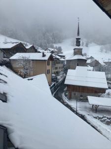 una ciudad cubierta de nieve con una iglesia al fondo en Auberge le bois du cornet, en La Forclaz