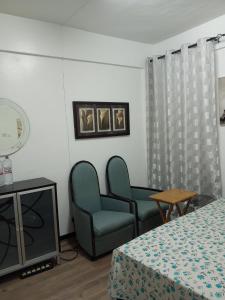 um quarto com duas cadeiras e uma cama e uma televisão em Haven Apartment em Mombasa