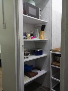a kitchen pantry with white shelves and a microwave at Haven Apartment in Mombasa