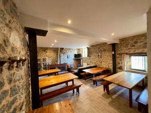 um quarto com mesas de madeira e uma parede de pedra em Albergue Valle de Arbas em Cubillas de Arbas