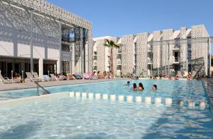 a swimming pool in a building with people in it at Hôtel Nakara by Odalys in Cap d'Agde