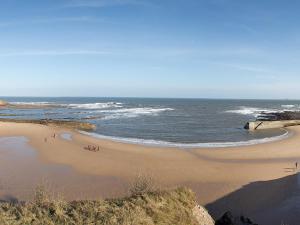 a beach with people on the sand and the ocean at Seafront Apartments in North Shields