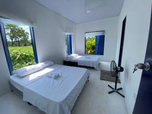 Habitación blanca con 2 camas y espejo. en Villa Santorini, en Cumaral