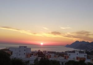 a sunset over the ocean and a city at Laurel Apartments in Bar