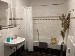 a bathroom with a sink and a tub and a shower at Cityliebe in Magdeburg