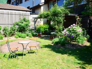 einen Garten mit einem Tisch, Stühlen und Blumen in der Unterkunft L'Eau Forte - maison d'hôtes in Saint-Blaise