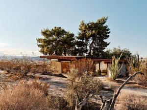 uma casa no meio de um deserto com árvores em Marmol Radziner's Modernist Cabin - Joshua Tree em Joshua Tree