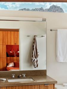 een badkamerspiegel met een wastafel en een slaapkamer bij Marmol Radziner's Modernist Cabin - Joshua Tree in Joshua Tree