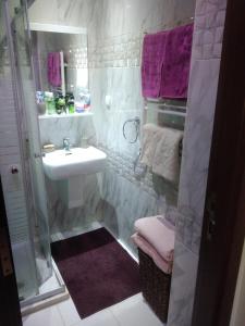 a bathroom with a sink and a shower with purple towels at Yasmina in Ariana