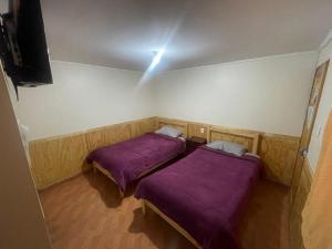 卡拉馬的住宿－Hostal Las Ñipas，配有紫色毯子的小客房内的两张床