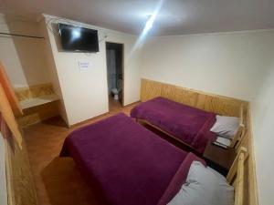 two beds in a room with purple sheets at Hostal Las Ñipas in Calama